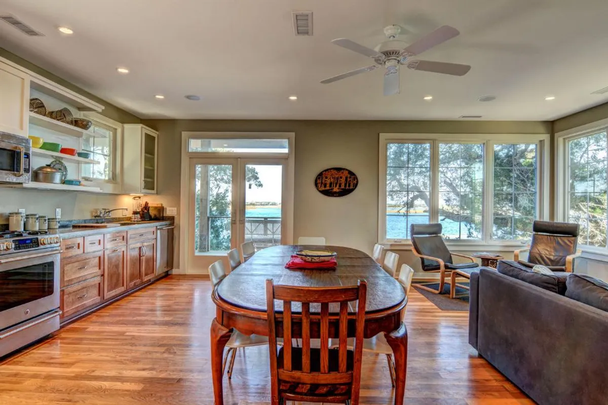 This image highlights a dining table set near large windows, blending a comfortable seating area with ample natural light. The arrangement encourages family meals, game nights, and social gatherings, all set against the backdrop of sunset-lit views.